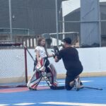 Coach montre à une jeune gardienne de dek hockey comment positionner son gant en position debout
