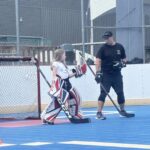 Coach montre à une jeune gardienne de dek hockey comment positionner en position debout